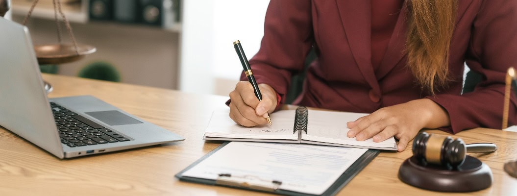 Junge asiatische Anwältin, die am Schreibtisch juristische Dokumente durchgeht und Zuverlässigkeit und Engagement im juristischen Beruf verkörpert, liest eine Anzeige. Gericht, das den Angeklagten nach dem Strafrecht verurteilt