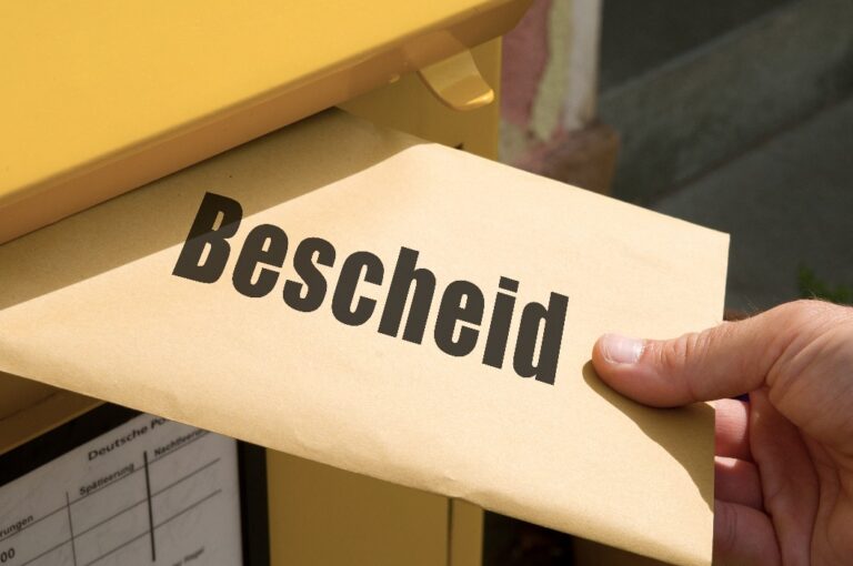 Briefn mit der aufschrift "Bescheid" wird in einen Briefkasten eingeworfen.
